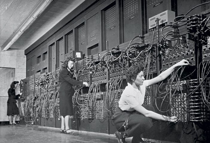 ca. 1940s --- Computer operators program ENIAC, the first electronic digital computer, by plugging and unplugging cables and adjusting switches. | Location: Mid-Atlantic USA. --- Image by © CORBIS